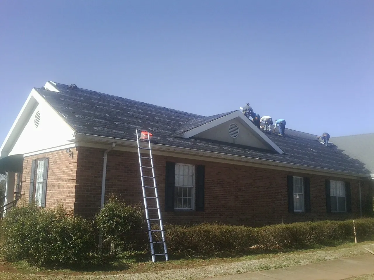 Crew tearing shingles off a brick ranch roof with a ladder set — Metal Roof Repair work by our crew in Villa Park