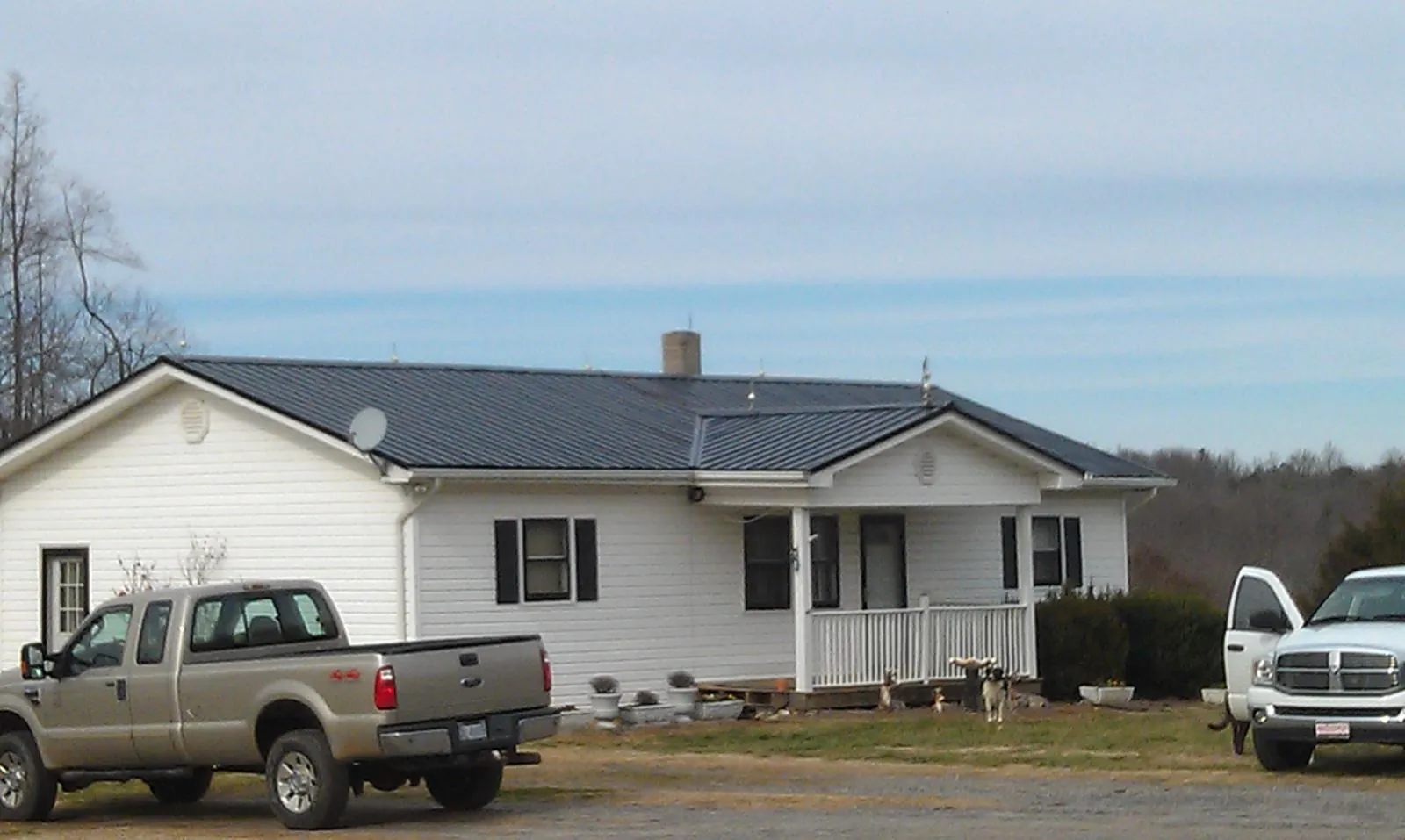 Finished dark metal roof on a white ranch home with work trucks parked in Villa Park